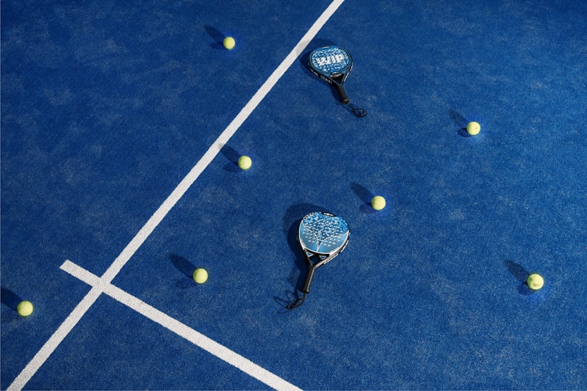 Overhead view of padel rackets and balls on a blue court