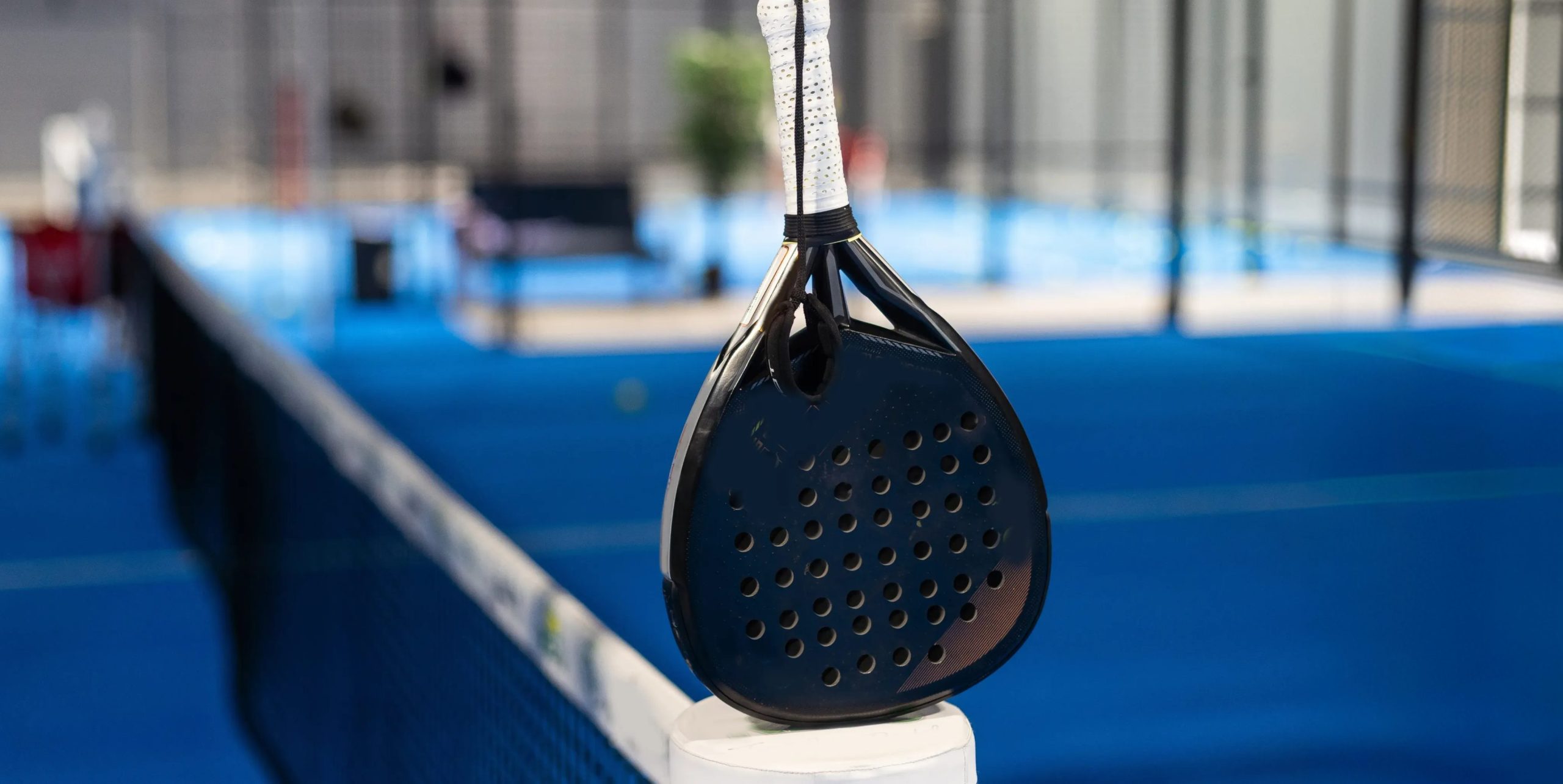 Padel racket hanging over the net at an indoor court